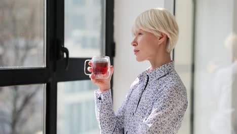 woman drinking tea and looking out the window