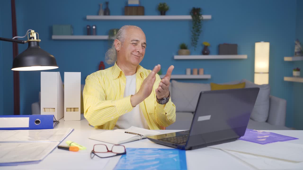 Home office worker old man applauding what he sees on laptop.