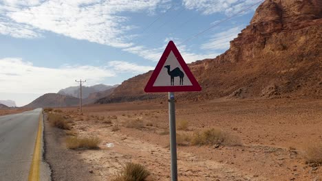 Una-Señal-De-Precaución-En-La-Carretera-De-Camellos-En-Un-Ambiente-Remoto,-Seco-Y-árido-Desértico-Con-Montañas-Rocosas-Y-Escarpadas-En-Jordania,-Oriente-Medio