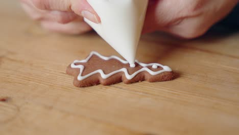 decorating gingerbread cookies for christmas, closeup macro shot making handmade festive new year sweets and cookies with white glaze icing