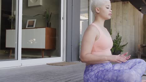 mujer biracial enfocada practicando yoga y meditando en el jardín en cámara lenta