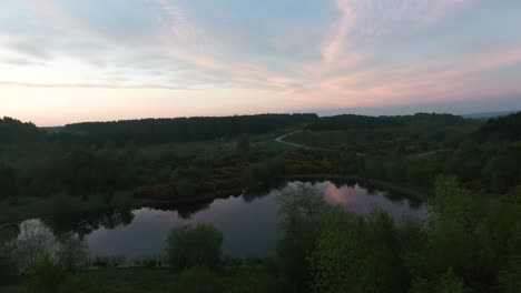 Stiller-See-In-Einem-Landschaftspark-In-Der-Abenddämmerung-An-Einem-Sonnenuntergangsabend,-Der-Eine-Aufschlussreiche-Luftaufnahme-Mit-Leichter-Parallaxe-Herstellt