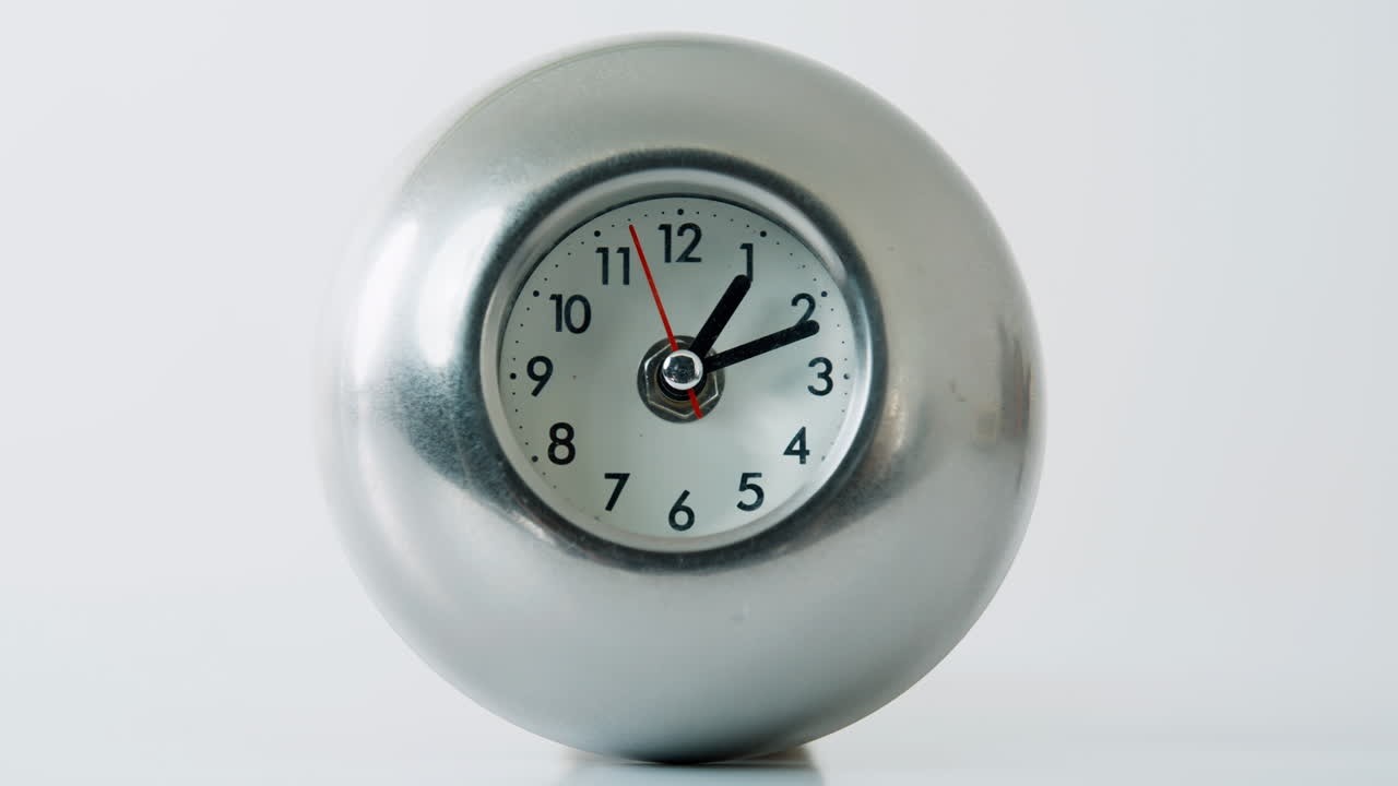 Metal clock ticking white studio space closeup. Hour and minute hands moving