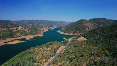 car driving on a scenic road through the forest along the lake on a sunny day