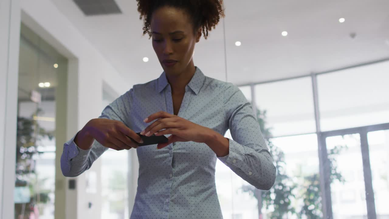 Mixed race businesswoman taking photos with smartphone in office