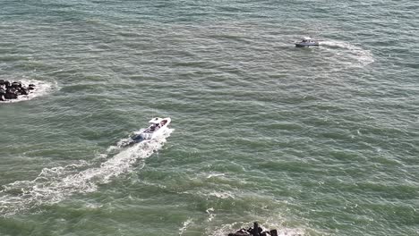 primer plano de varios barcos que salen de la entrada de rudee y reducir el zoom para el contexto