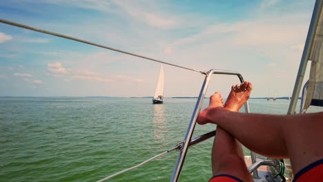 Close-Up-Shot-Relaxed-Traveler-Man-Legs-on-Motorboat-on-Beautiful-Island-and-Mountain-Carefree-Concept