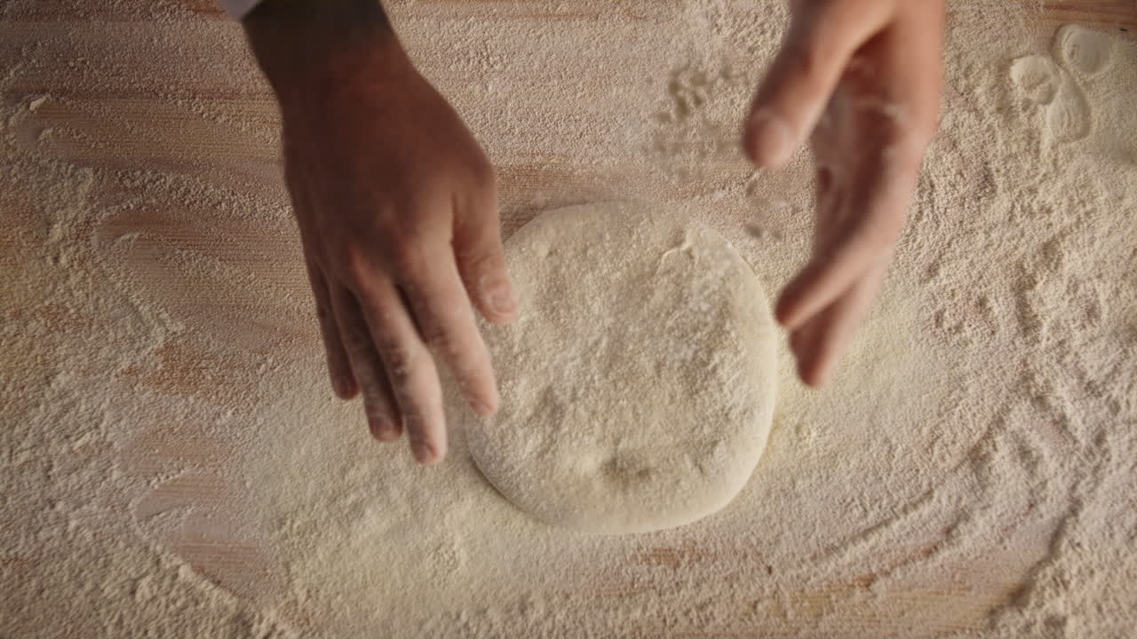 Mani dello chef che impastano l'impasto nella cucina di una pizzeria italiana.