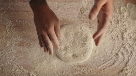 las manos del chef cocinando pan de masa en la cocina de un restaurante de pizza italiano.