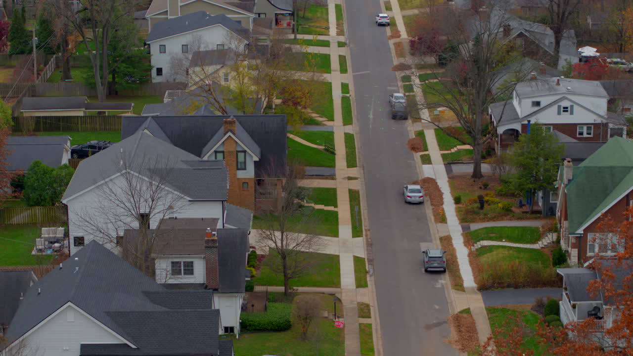 Beautiful aerial push down a charming neighborhood street in St. Louis, Missouri, during autumn. Captures fall foliage, cozy homes, and suburban serenity on a seasonal day.