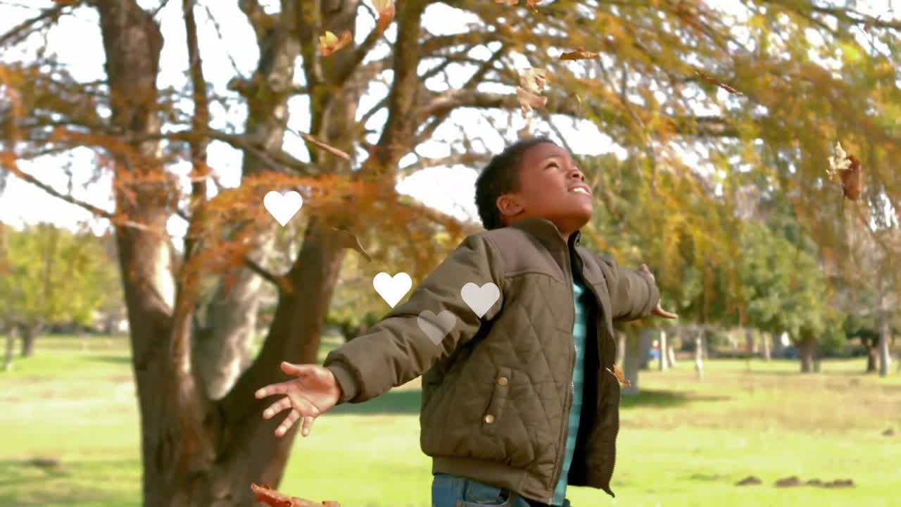 Niño sosteniendo hojas de otoño en un parque, levantando los brazos y soltando las hojas para marketing estacional