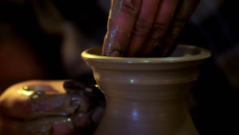 male hands forming clay pitcher neck. ceramic dishes on potter wheel