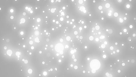 glowing white christmas light particles falling on grey bokeh background