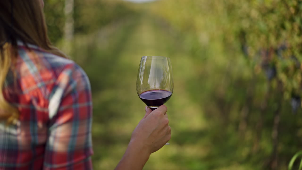 Woman holding a glass of red wine in a vineyard