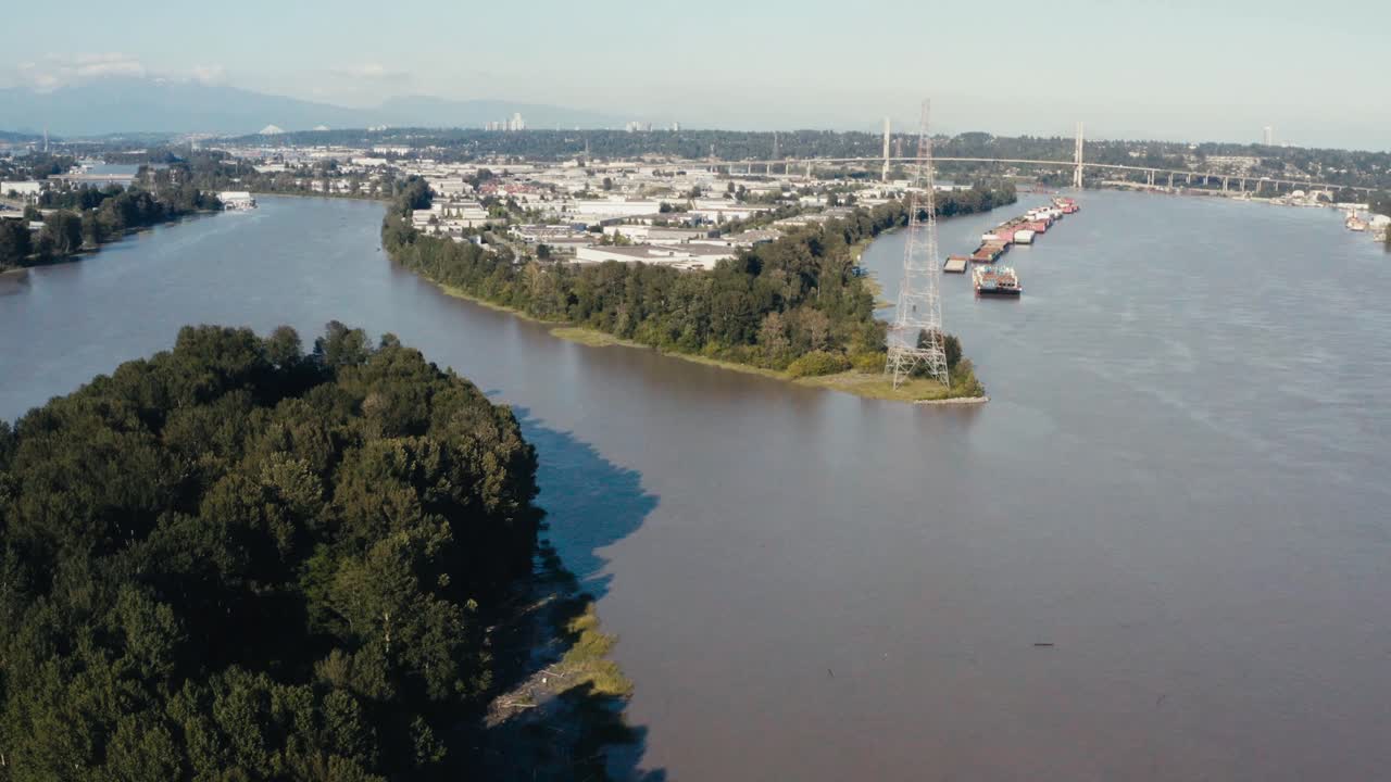 Aerial Fly over an island indangered wild life in the midst of big industry import export harbor for freighters barges cargo for natural resources hemp lumber produce canibas a river ocean connect 2-3