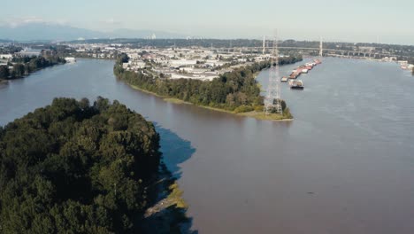 aerial fly over an island indangered wild life in the midst of big industry import export harbor for freighters barges cargo for natural resources hemp lumber produce canibas a river ocean connect 2-3