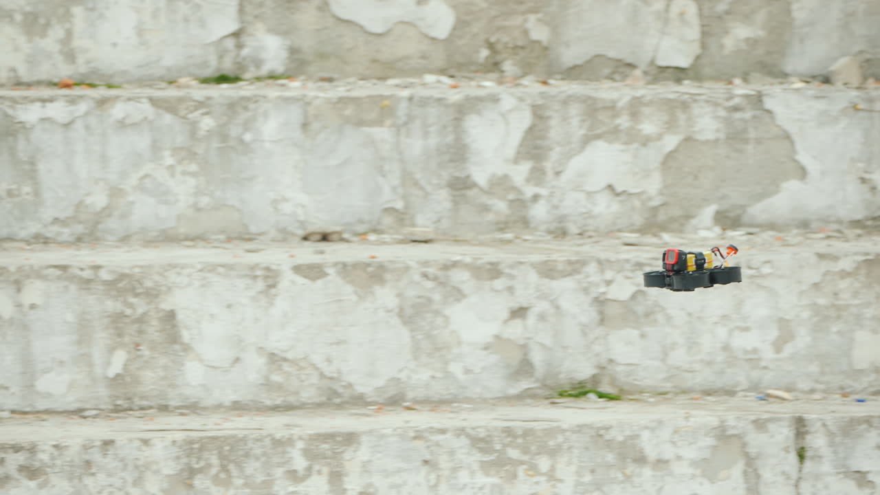 카메라가 달린 스포츠 드론이 흰 벽을 따라 빠르게 날아간다