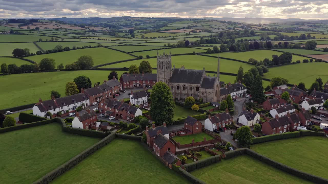 Aerial video captures a picturesque village with a church at the center, surrounded by lush green