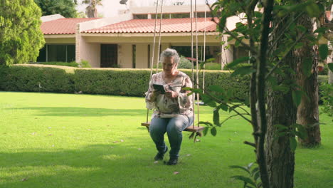 mujer de cabello gris sentada afuera y leyendo un libro electrónico