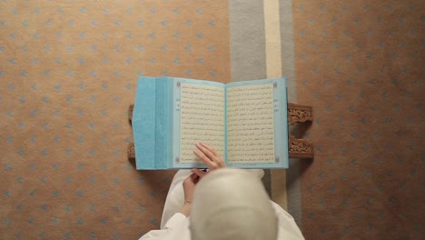 Overhead-shot-of-hijabi-woman-reading-Quran-from-mushaf-on-stand