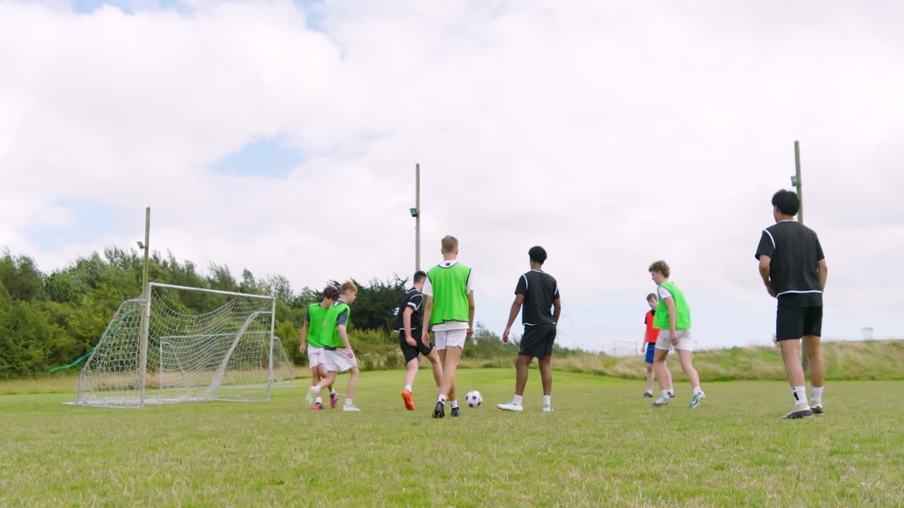 Multiracial male soccer players playing soccer, running after and passing ball on pitch