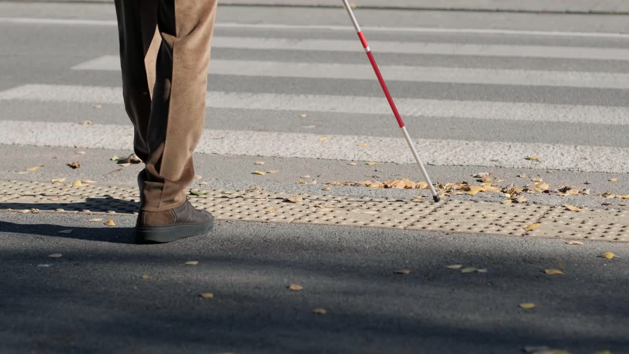 Lone blind man detecting tactile tiles, walking to pedestrian crossing safe road