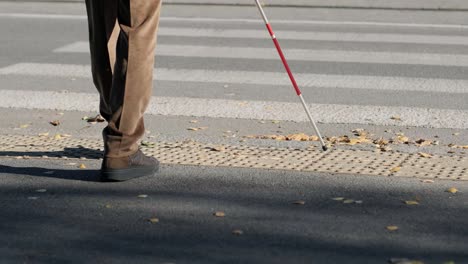 lone blind man detecting tactile tiles, walking to pedestrian crossing safe road