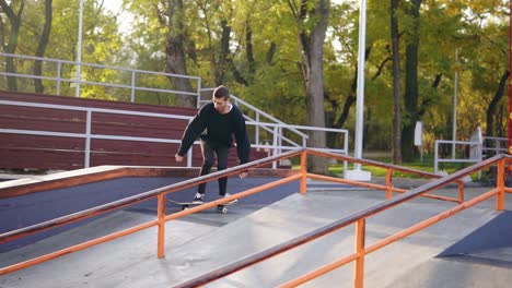 joven patinador extremo escuchando la música en los auriculares moliendo el riel en el skatepark. disparo en cámara lenta