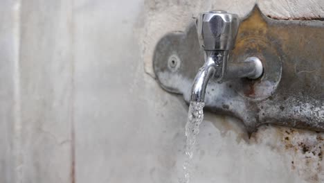 primer plano de un grifo de agua viejo y oxidado con agua corriendo
