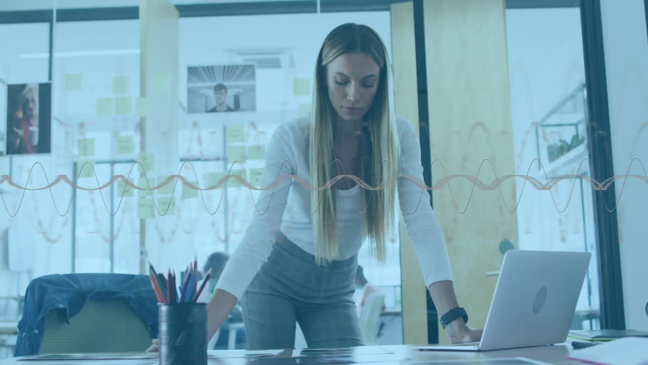 Animación de ondas de sonido sobre una mujer trabajando en un escritorio en una oficina moderna.