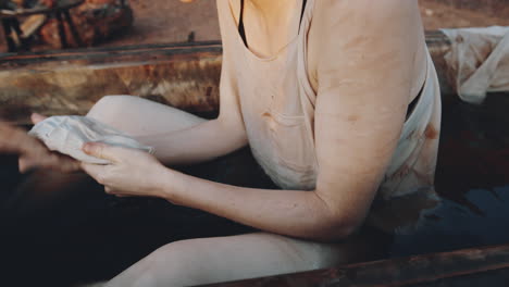 woman cleaning face in bath with dirty water in dystopian world