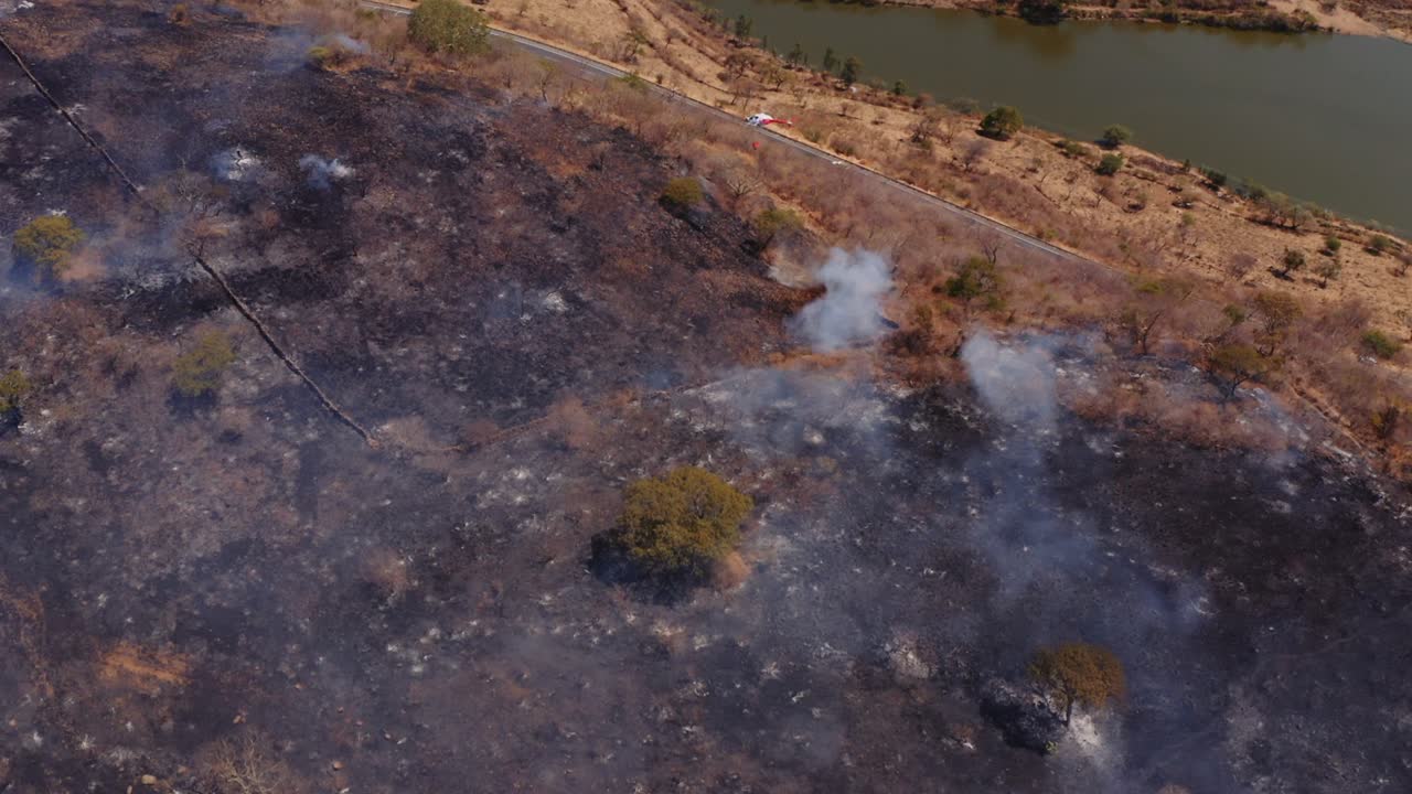 vista aérea con vistas a helicóptero extinción de incendios forestales desastre natural en la ladera de la colina de hierba seca humeante