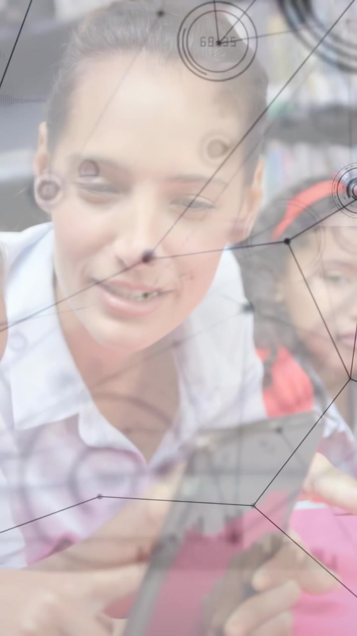 Vertical video: Teacher leaning, guiding kids tapping pink tablet while tech overlay showing lesson