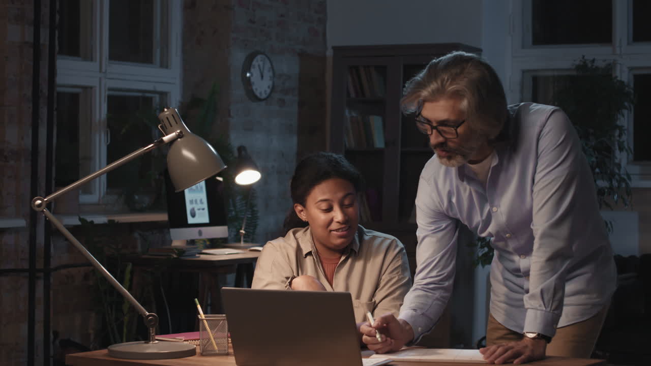 Due colleghi diversi che collaborano a una scrivania in ufficio di notte