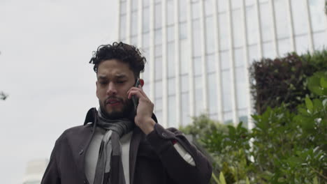 Close-up-on-handsome-business-man,-entrepreneur-rushes-down-the-stairs-of-business-office-building-while-talks-on-the-phone