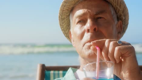 Front-view-of-active-senior-Caucasian-man-drinking-cocktail-on-the-beach-4k