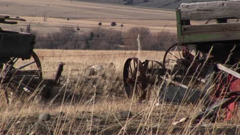 broken and abandoned farm machinery rest in a field that overlooks the dry prairie beyond