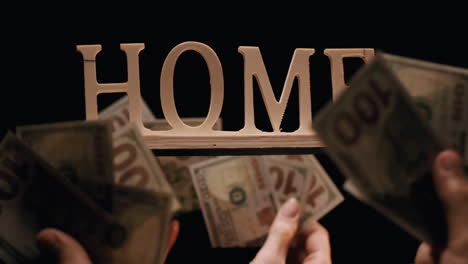 Multiple-Hands-Bidding-For-"Home"-Sign,-With-Hundred-Dollar-Bills