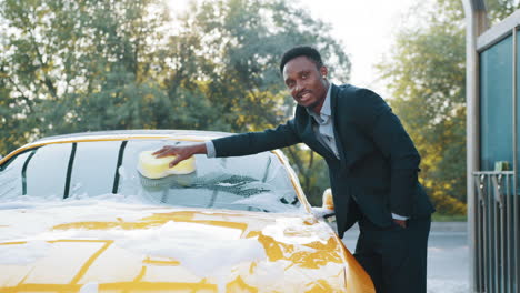 hombre lavando un coche amarillo