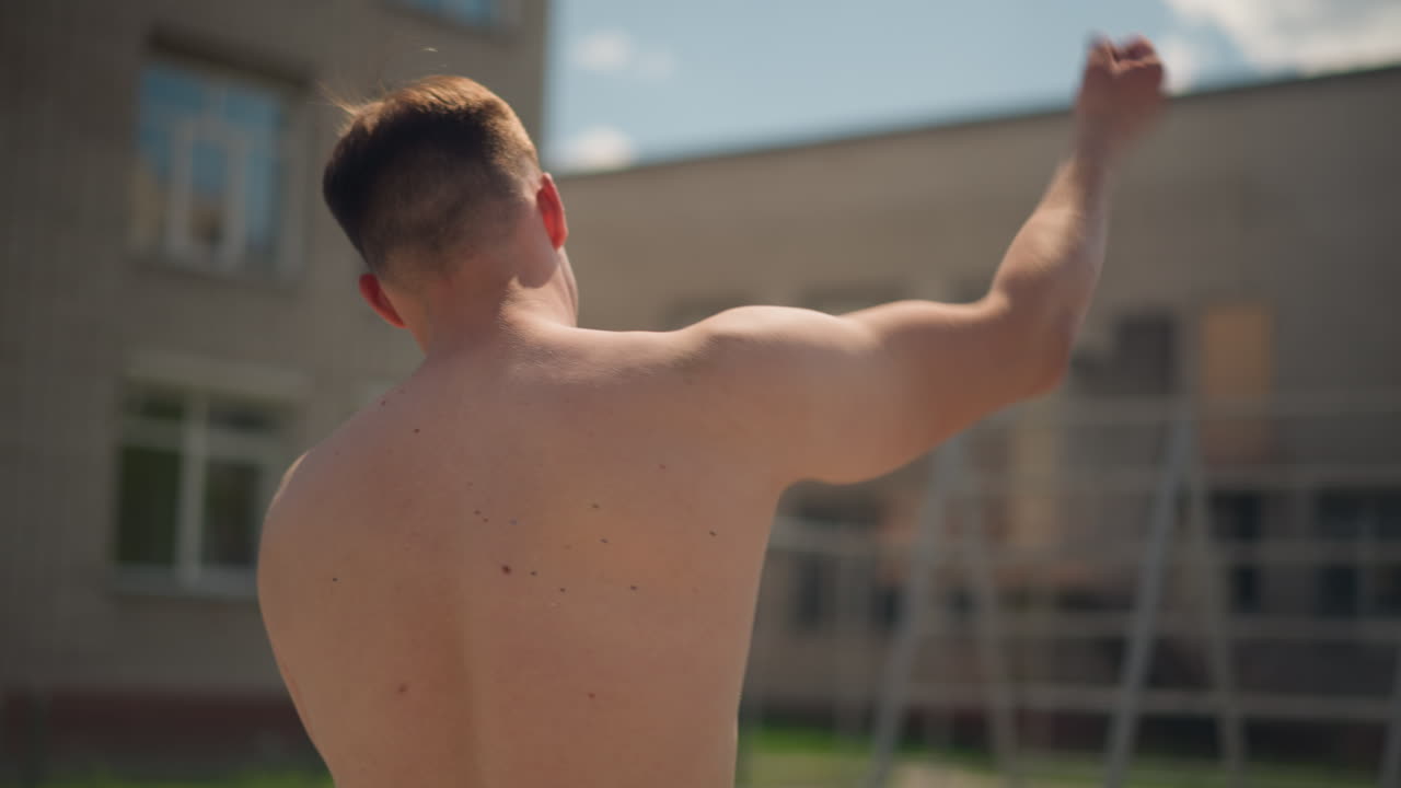 Joven relajándose, hombre con ropa mínima en un parque urbano, joven descansando en un parque urbano, joven sin camiseta tomándose un respiro en una zona verde de la ciudad