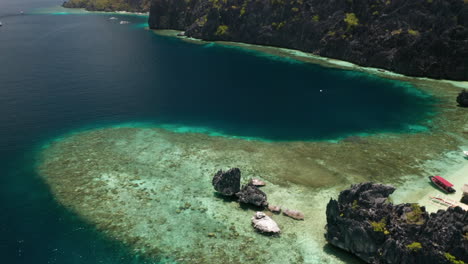 aerial tilting down on tropical water by matinloc island, el nido, palawan, pilippines