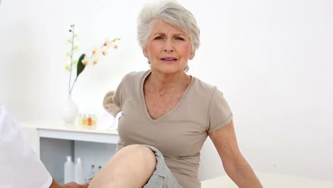 Injured-patient-wincing-while-doctor-checks-her-knee