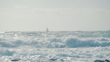 sea waves hitting the shore with a big red buoy float in the background