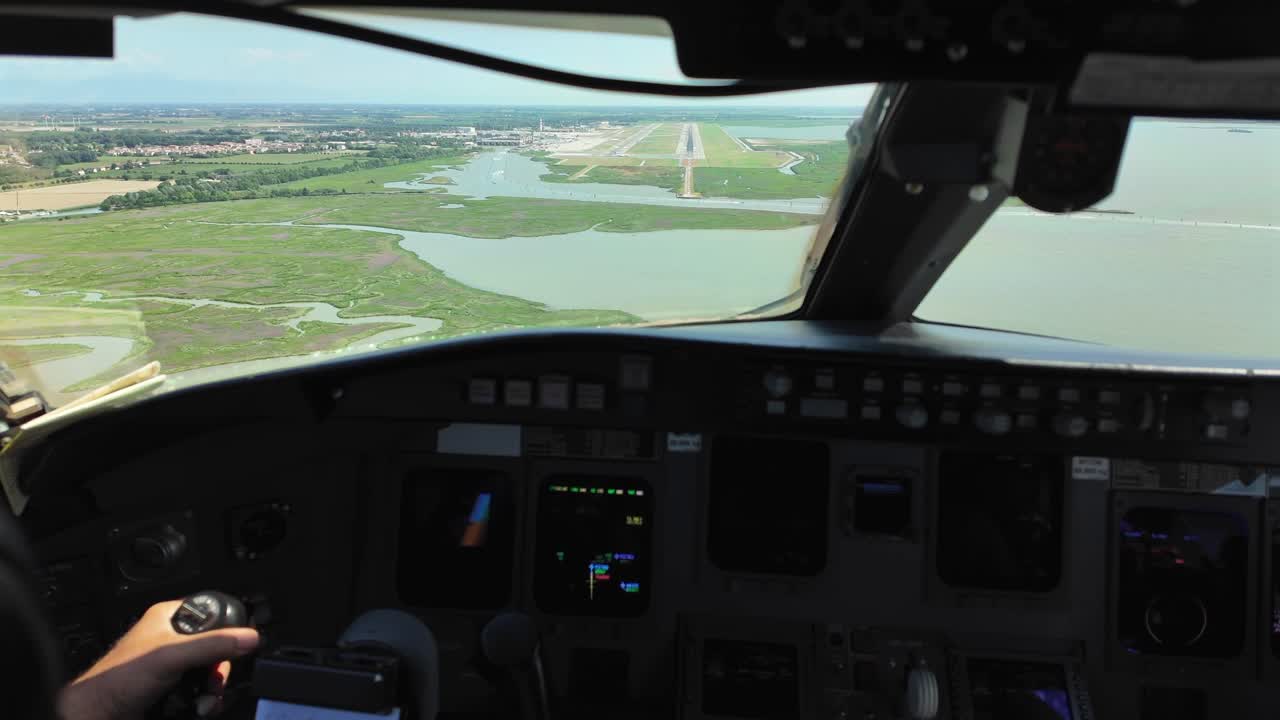 подход к аэропорту венеции, виденный из кабины пилота самолета, летящего над лагуной с взлетно-посадочной полосой впереди