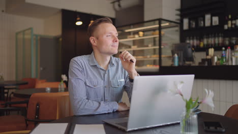 Close-up-portrait-of-ponder-young-man-in-office.-Designer-plans-his-work-and-holding-a-pencil-in-his-hand.-Shooting-is-slow-motion-from-below.-Thoughtful-serious-man-sit-with-laptop-thinking-solution