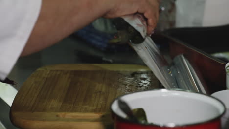 old georgian chef woman wrapping fish in baking tin foil in kitchen