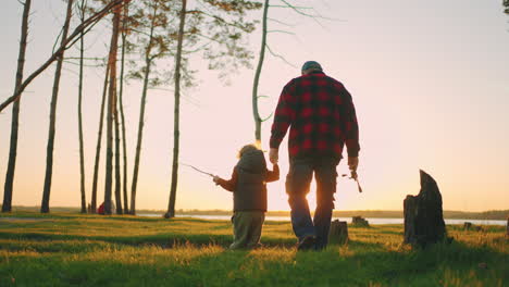 La-Familia-Feliz-Está-Pasando-El-Fin-De-Semana-En-La-Naturaleza,-El-Abuelo-Y-El-Niño-Caminan-Yendo-A-Pescar-En-La-Costa-Del-Río.