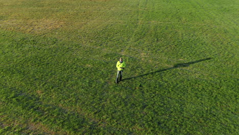 Toma-Aérea-De-Un-Dron-Dando-Vueltas-Alrededor-De-Un-Hombre-Parado-En-El-Campo