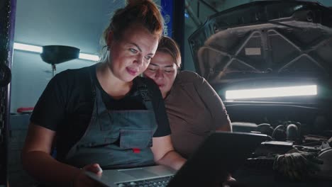 women mechanics inspecting a car with laptop