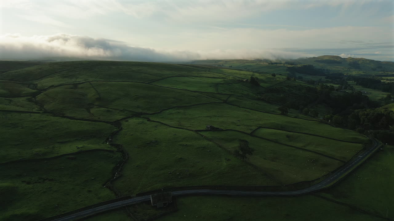 Indledende droneoptagelse over Yorkshire Dales' marker og bakker med lavthængende skyer.